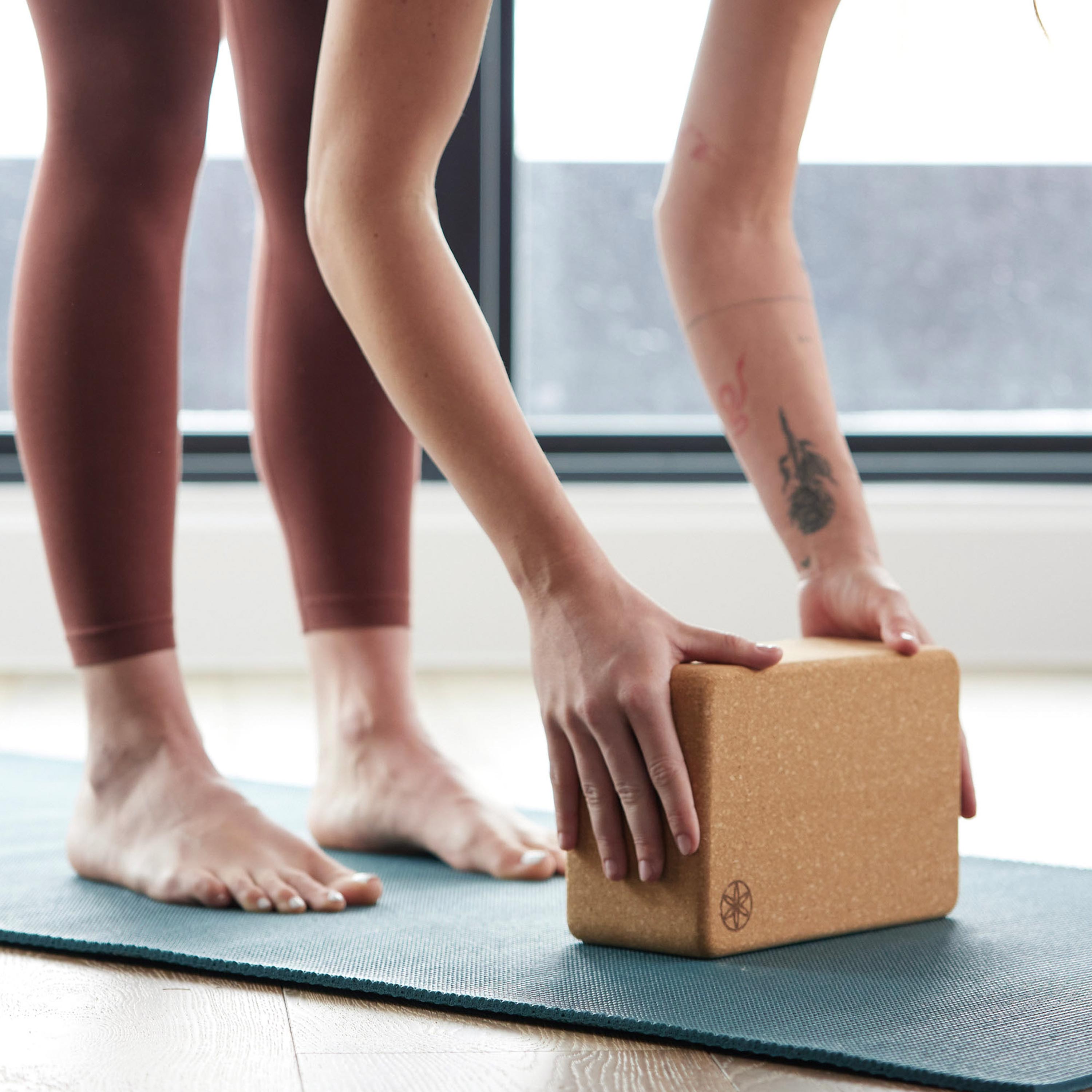 Up close image of person using the Performance Cork Block while in a forward bend.  Both hands are on the block.